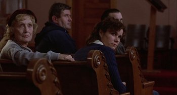 Movie still from “Hoosiers” (1986), directed by David Anspaugh – Three people sitting in pews in a church; Medium shot, Low angle