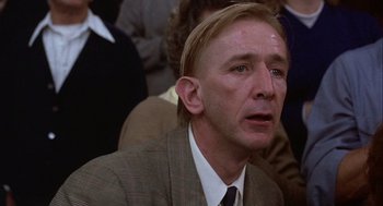 Movie still from “Hoosiers” (1986), directed by David Anspaugh – A person wearing a suit and tie; Close Up shot, Low angle