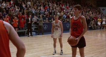 Movie still from “Hoosiers” (1986), directed by David Anspaugh – A group of young men playing a game of basketball; Wide shot, Over the shoulder angle
