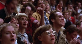 Movie still from “Hoosiers” (1986), directed by David Anspaugh – A group of people sitting in a room with their hands in the air; Close Up shot, Low angle