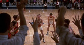 Movie still from “Hoosiers” (1986), directed by David Anspaugh – A group of young men playing a game of basketball; Wide shot, High angle