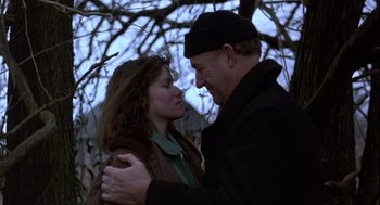 Movie still from “Hoosiers” (1986), directed by David Anspaugh – A man and a woman embracing each other in a wooded area; Close Up shot, Low angle
