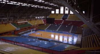 Movie still from “Hoosiers” (1986), directed by David Anspaugh – An indoor basketball court with a basketball hoop; Extreme Wide shot, High angle