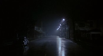 Movie still from “Hoosiers” (1986), directed by David Anspaugh – A dark street at night lit by street lights; Extreme Wide shot, Low angle