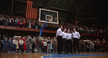 Movie still from “Hoosiers” (1986), directed by David Anspaugh – A group of men standing on top of a basketball court; Extreme Wide shot, High angle