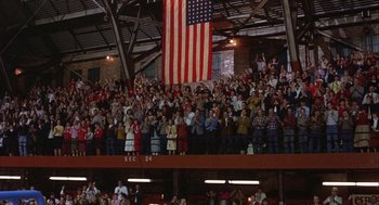 Movie still from “Hoosiers” (1986), directed by David Anspaugh – A crowd of people standing under an american flag in an arena; Extreme Wide shot, High angle