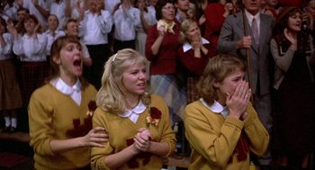 Movie still from “Hoosiers” (1986), directed by David Anspaugh – A group of people that are sitting in front of a crowd; Medium shot, Low angle