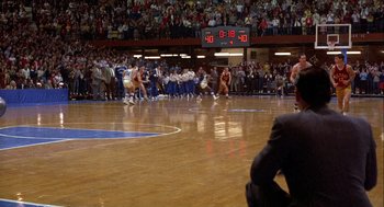 Movie still from “Hoosiers” (1986), directed by David Anspaugh – A group of people on a basketball court with a crowd watching; Extreme Wide shot, High angle