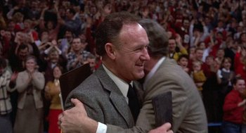 Movie still from “Hoosiers” (1986), directed by David Anspaugh – Two men hugging in front of an audience; Medium shot, Over the shoulder angle
