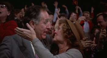 Movie still from “Hoosiers” (1986), directed by David Anspaugh – An older man and woman hugging in front of an audience; Close Up shot, High angle