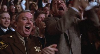 Movie still from “Hoosiers” (1986), directed by David Anspaugh – A group of people that are sitting in a crowd; Medium shot, Low angle