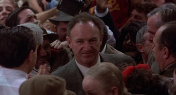 Movie still from “Hoosiers” (1986), directed by David Anspaugh – A man in a suit and tie surrounded by a crowd; Close Up shot, Over the shoulder angle