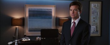 Movie still from “Horrible Bosses” (2011), directed by Seth Gordon – A man in a suit and tie standing in front of a laptop; Medium shot, Over the shoulder angle