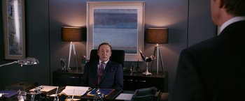 Movie still from “Horrible Bosses” (2011), directed by Seth Gordon – A man sitting at a desk in front of a painting; Medium shot, Over the shoulder angle