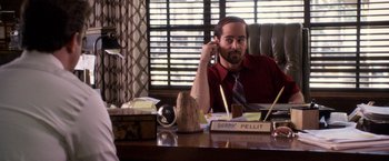 Movie still from “Horrible Bosses” (2011), directed by Seth Gordon – A man sitting at a desk talking on the phone; Medium shot, Over the shoulder angle