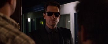 Movie still from “Horrible Bosses” (2011), directed by Seth Gordon – A man in a suit and sunglasses looking at the camera; Close Up shot, Over the shoulder angle