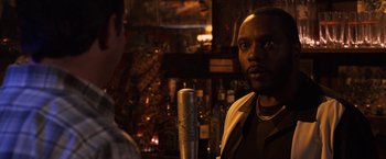 A man standing in front of a microphone in front of a bar