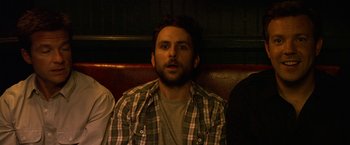 Movie still from “Horrible Bosses” (2011), directed by Seth Gordon – A man sitting on a red leather couch with two other people; Close Up shot, High angle