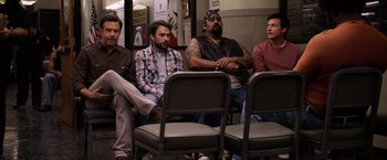 Movie still from “Horrible Bosses” (2011), directed by Seth Gordon – A group of men sitting next to each other in front of chairs; Wide shot, High angle
