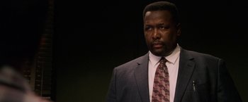 Movie still from “Horrible Bosses” (2011), directed by Seth Gordon – A man in a suit and tie standing in front of a black background; Close Up shot, Over the shoulder angle
