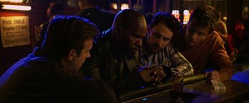 Movie still from “Horrible Bosses” (2011), directed by Seth Gordon – A group of men sitting at a table in front of a bottle; Medium shot, Over the shoulder angle