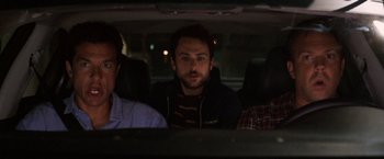 Movie still from “Horrible Bosses” (2011), directed by Seth Gordon – Three men sitting in the back seat of a car at night; Medium shot, Over the shoulder angle