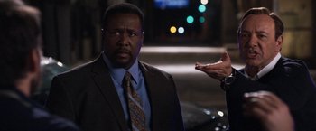 Movie still from “Horrible Bosses” (2011), directed by Seth Gordon – A man wearing a suit and tie standing next to a car; Close Up shot, Over the shoulder angle
