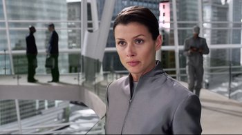 Movie still from “I, Robot” (2004), directed by Alex Proyas – A woman wearing a gray jacket standing in front of a building; Medium shot, Over the shoulder angle