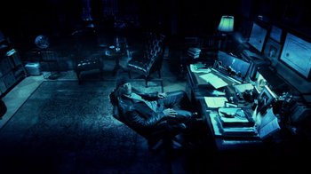 Movie still from “I, Robot” (2004), directed by Alex Proyas – A man sitting on a chair in a dark room; Wide shot, High angle