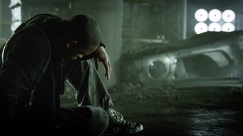 Movie still from “I, Robot” (2004), directed by Alex Proyas – A man sitting on the ground with his head on his knees; Close Up shot, Low angle