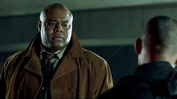 Movie still from “I, Robot” (2004), directed by Alex Proyas – A man in a brown jacket and a red tie; Close Up shot, Over the shoulder angle