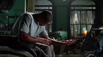 Movie still from “I, Robot” (2004), directed by Alex Proyas – A man sitting on a couch with his hands up; Medium shot, High angle