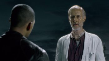 Movie still from “I, Robot” (2004), directed by Alex Proyas – A man in a white lab coat is looking at another man in a leather jacket; Close Up shot, Over the shoulder angle