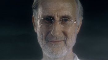 Movie still from “I, Robot” (2004), directed by Alex Proyas – An older man with glasses is smiling for the camera; Close Up shot, Over the shoulder angle