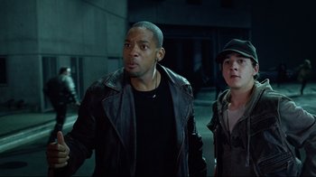 Movie still from “I, Robot” (2004), directed by Alex Proyas – A man and a woman walking in a dark area; Medium shot, Over the shoulder angle