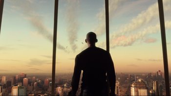 Movie still from “I, Robot” (2004), directed by Alex Proyas – A man standing in front of a window looking out at a city skyline; Wide shot, Low angle