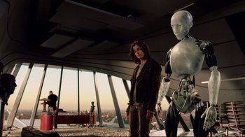 Movie still from “I, Robot” (2004), directed by Alex Proyas – A man standing next to a robot in a room; Medium shot, Low angle