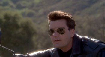Movie still from “Hot Shots!” (1991), directed by Jim Abrahams – A person wearing sunglasses and a leather jacket; Close Up shot, Over the shoulder angle