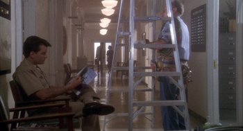 Movie still from “Hot Shots!” (1991), directed by Jim Abrahams – Two men are working in an empty room; Wide shot, Low angle