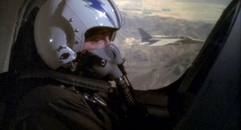 Movie still from “Hot Shots!” (1991), directed by Jim Abrahams – A man in a fighter pilot's helmet looking out the window of an aircraft; Medium shot, High angle
