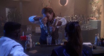 Movie still from “Hot Shots!” (1991), directed by Jim Abrahams – A man pouring a drink into a wine glass; Medium shot, High angle