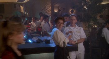 Movie still from “Hot Shots!” (1991), directed by Jim Abrahams – A group of people standing around a bar; Medium shot, Over the shoulder angle