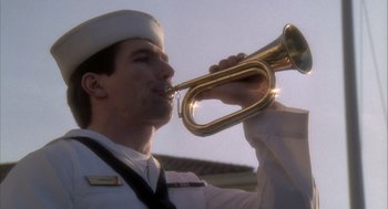 Movie still from “Hot Shots!” (1991), directed by Jim Abrahams – A man in a sailor's uniform blowing into a trumpet; Close Up shot, Low angle