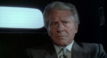 Movie still from “Hot Shots!” (1991), directed by Jim Abrahams – An older man wearing a suit and tie in the back of a car; Close Up shot, Low angle