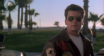 Movie still from “Hot Shots!” (1991), directed by Jim Abrahams – A man wearing sunglasses standing in front of palm trees; Close Up shot, Low angle