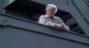 Movie still from “Hot Shots!” (1991), directed by Jim Abrahams – An older man leaning on a railing looking out of a window; Medium shot, Low angle
