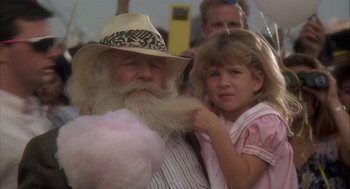 Movie still from “Hot Shots!” (1991), directed by Jim Abrahams – A young girl is brushing a man's beard with cotton candy; Close Up shot, Over the shoulder angle