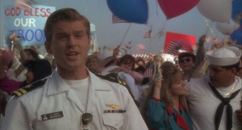 Movie still from “Hot Shots!” (1991), directed by Jim Abrahams – A man in a military uniform standing in front of a crowd of onlookers; Medium shot, Over the shoulder angle