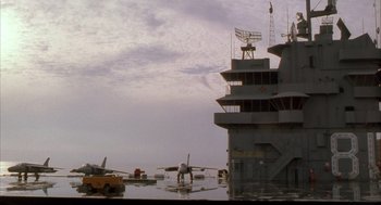 Movie still from “Hot Shots!” (1991), directed by Jim Abrahams – An airplane is sitting on the water next to an aircraft carrier; Extreme Wide shot, Low angle