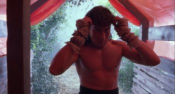 Movie still from “Hot Shots! Part Deux” (1993), directed by Jim Abrahams – A shirtless man with boxing gloves covering his ears; Close Up shot, Low angle